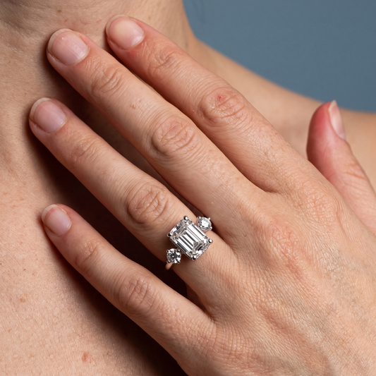 18 KT White Gold Emerald Cut Diamond Three Stone Engagement Ring with Hidden Halo - worn close-up