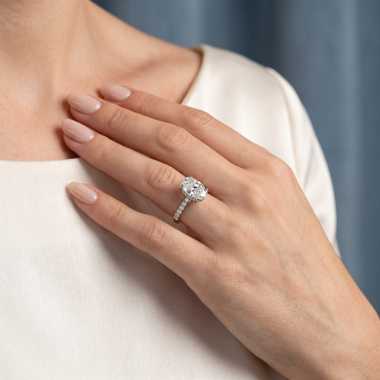 14 KT White Gold Oval Cut Diamond Solitaire Ring with Hidden Halo and Pave Band - worn close-up