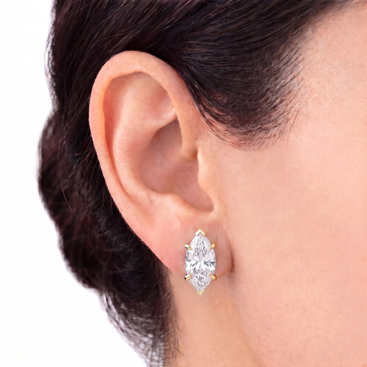 Marquise cut tiger-prong diamond stud earring in yellow gold worn on ear