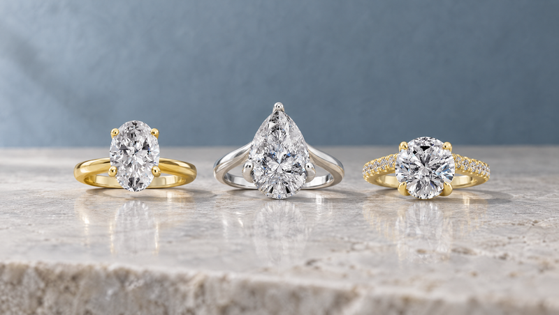 Three lab-grown diamond engagement rings in oval, pear and round shapes
