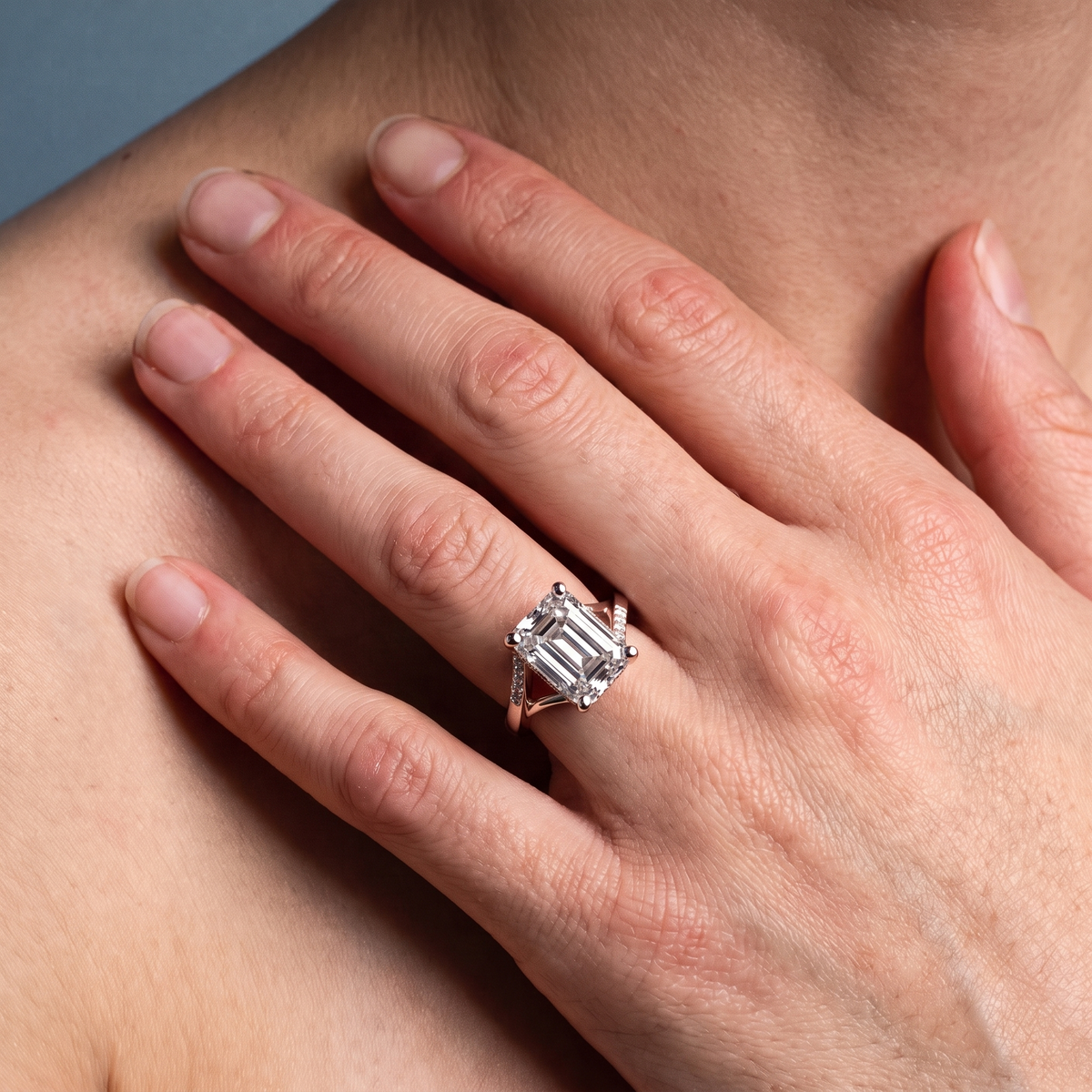 18 KT Rose Gold Emerald Cut Diamond Split Shank Engagement Ring with Hidden Halo - worn close-up