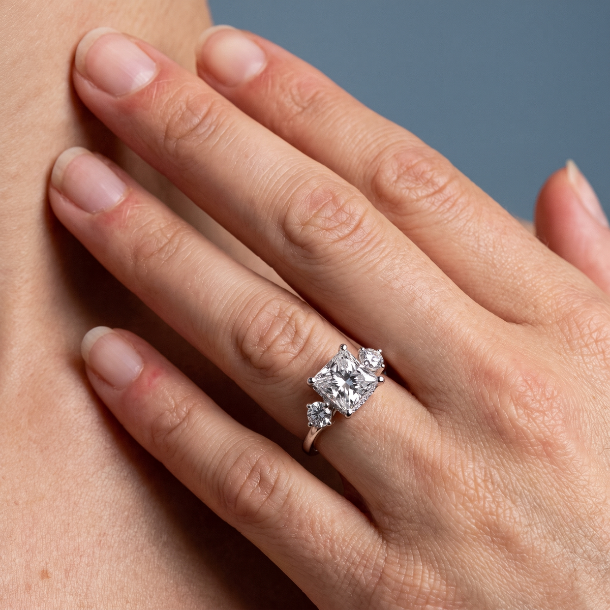 18 KT White Gold Princess Cut Diamond Three Stone Engagement Ring with Hidden Halo - worn close-up