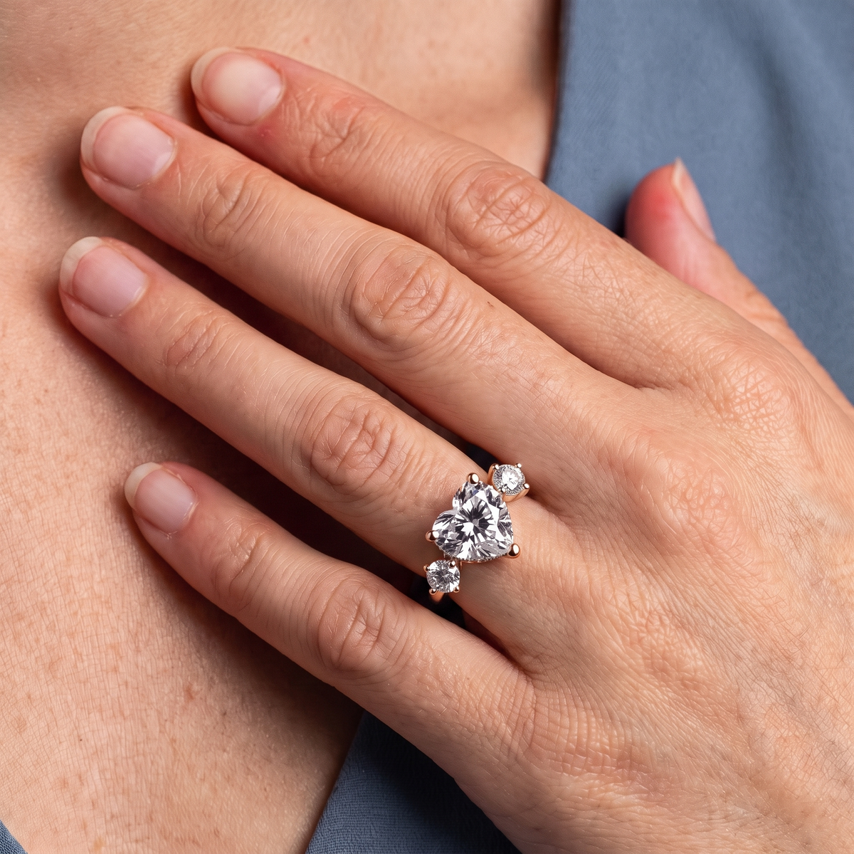 14 KT Rose Gold Heart Cut Diamond Three Stone Engagement Ring with Hidden Halo - worn close-up