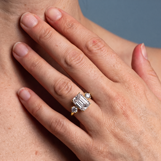 18 KT Yellow Gold Emerald Cut Diamond Three Stone Engagement Ring with Hidden Halo - worn close-up