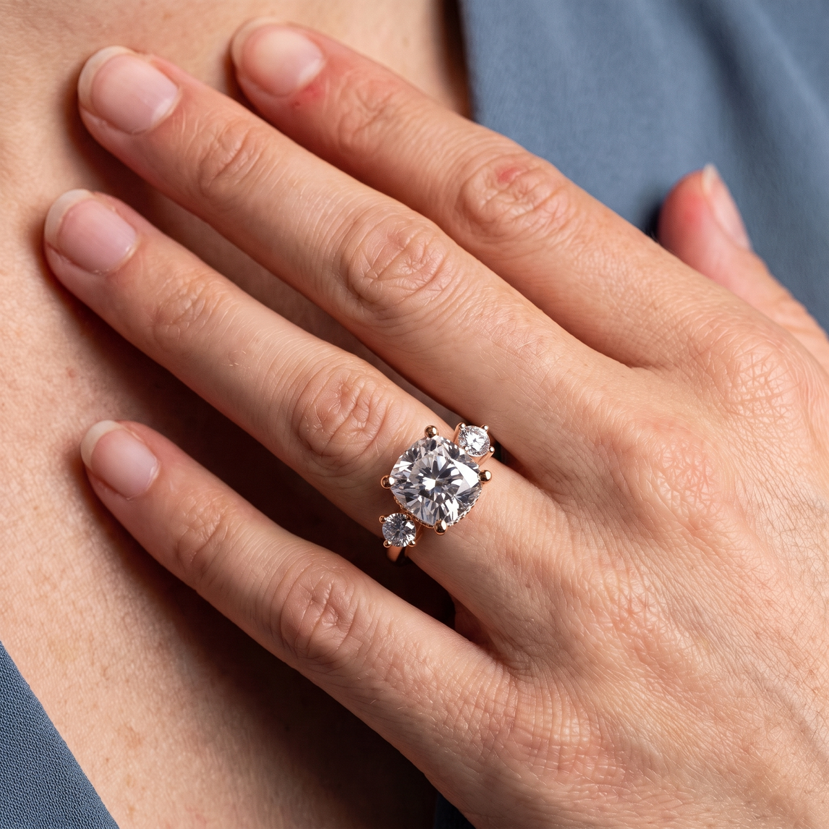 18 KT Rose Gold Cushion Cut Diamond Three Stone Engagement Ring with Hidden Halo - worn close-up
