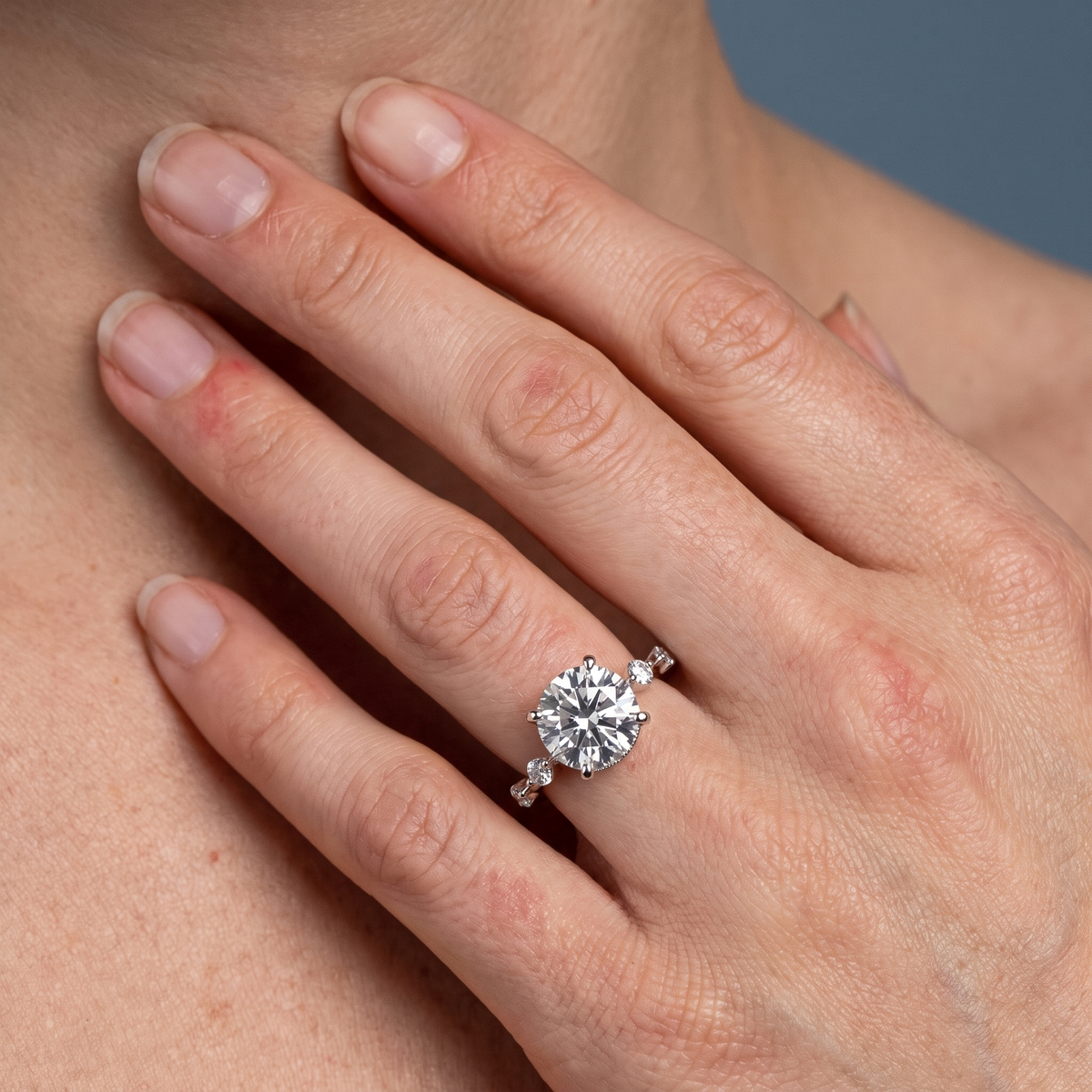 18 KT White Gold Round Cut Diamond Solitaire Ring with Floating Diamond Accents - worn close-up