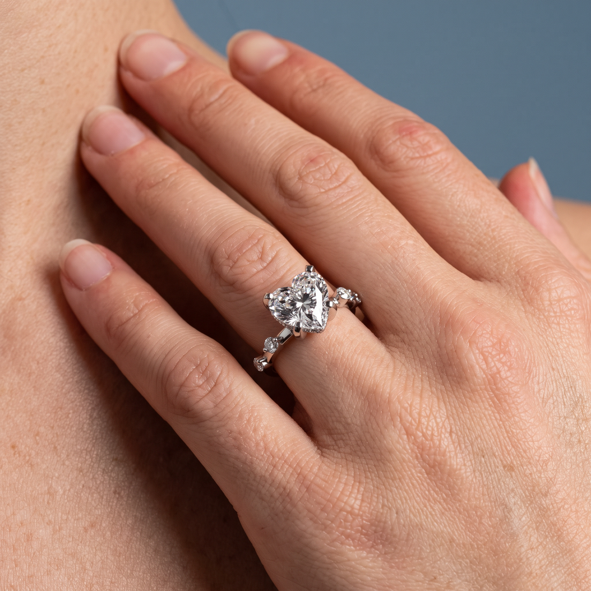 18 KT White Gold Heart Cut Diamond Solitaire Ring with Floating Diamond Accents - worn close-up