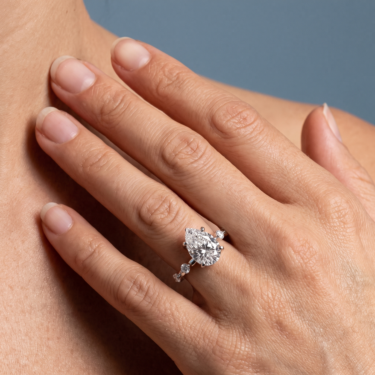 Platinum Pear Cut Diamond Solitaire Ring with Floating Diamond Accents - worn close-up