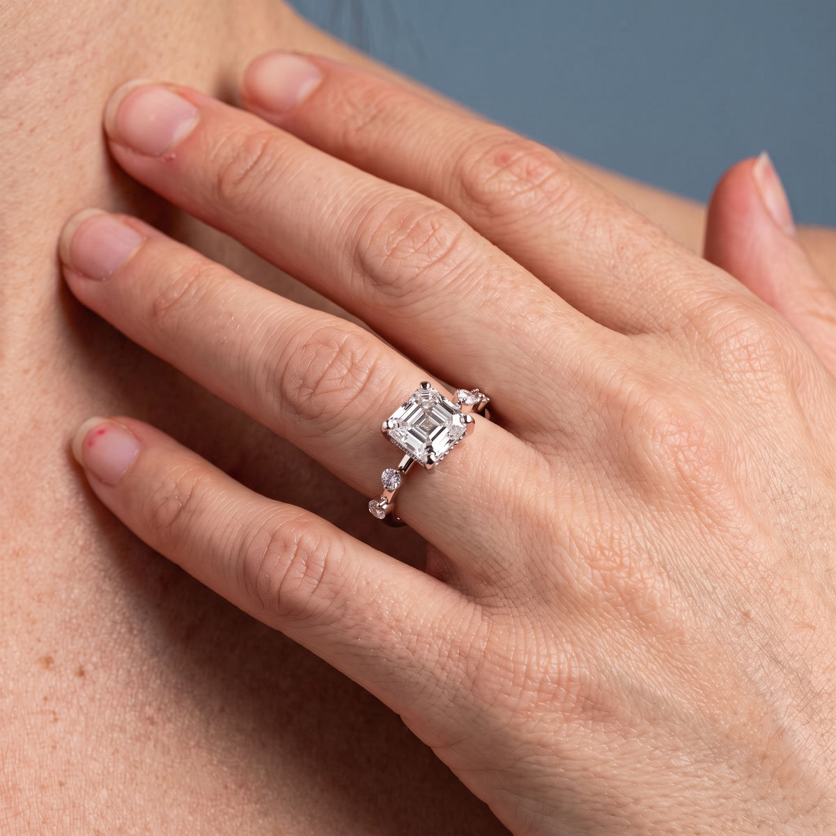 18 KT Rose Gold Asscher Cut Diamond Solitaire Ring with Floating Diamond Accents - worn close-up