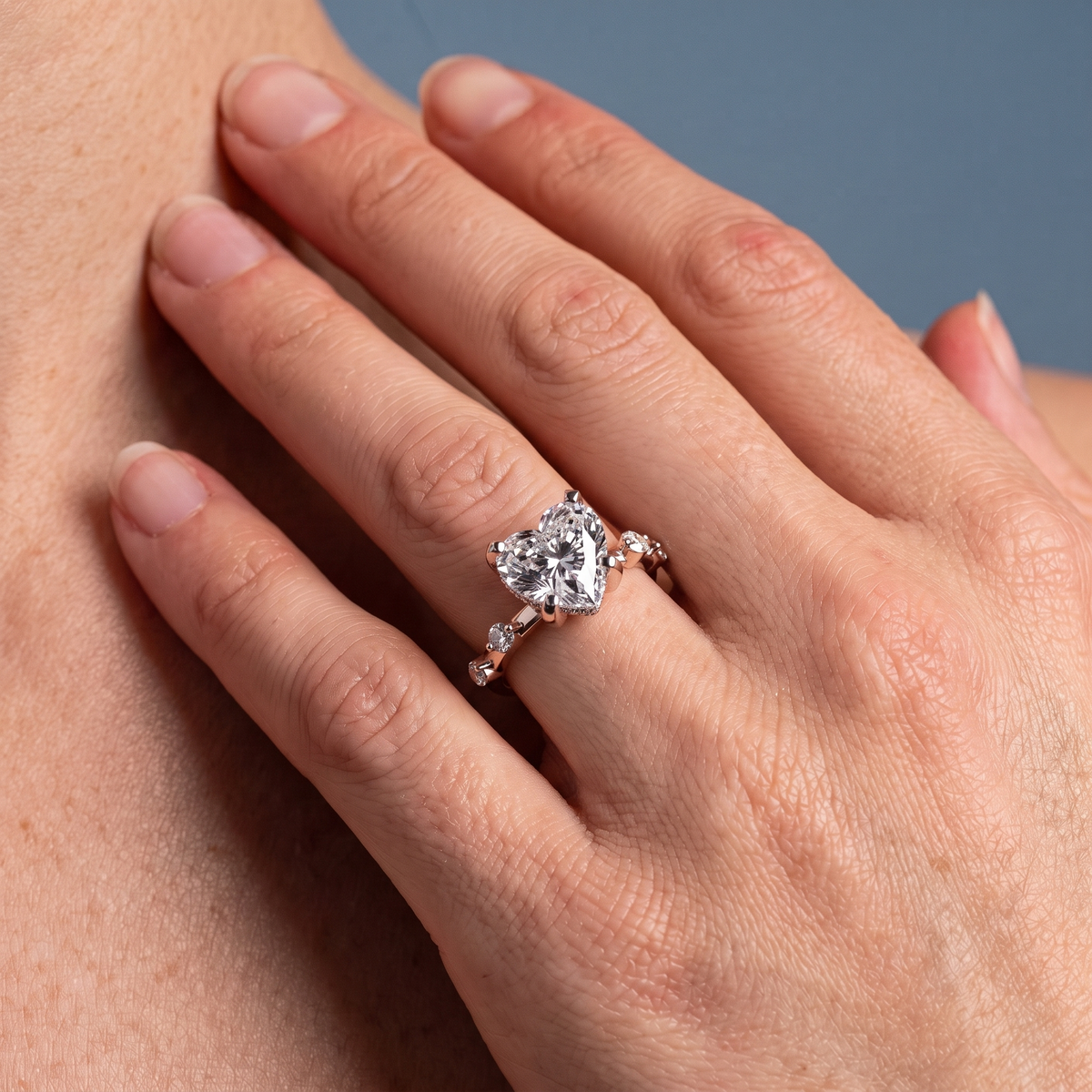 14 KT Rose Gold Heart Cut Diamond Solitaire Ring with Floating Diamond Accents - worn close-up