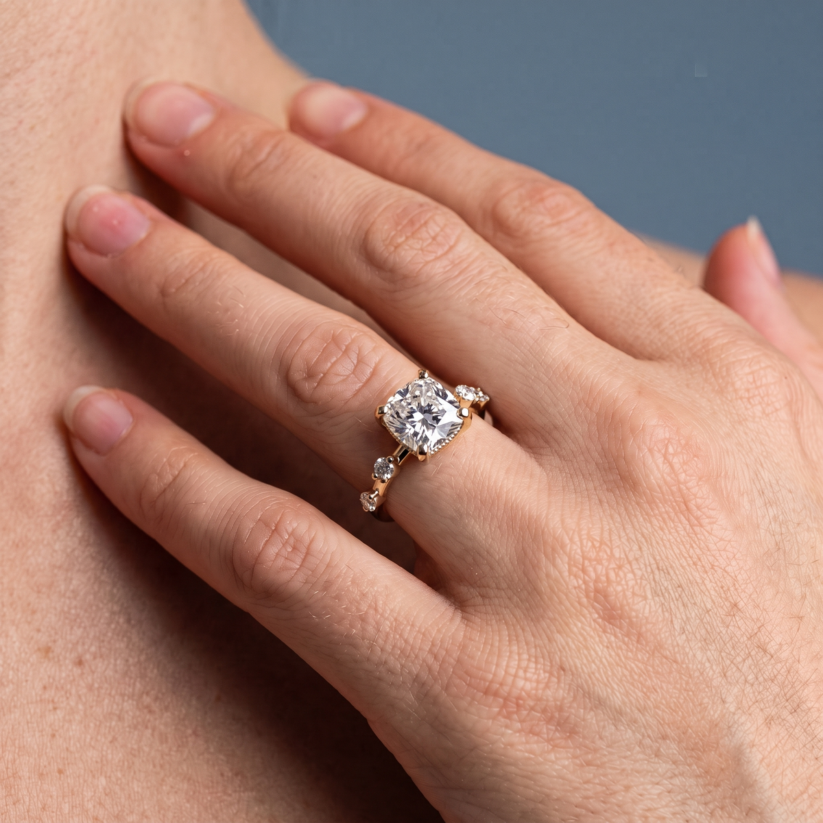 18 KT Yellow Gold Cushion Cut Diamond Solitaire Ring with Floating Diamond Accents - worn close-up