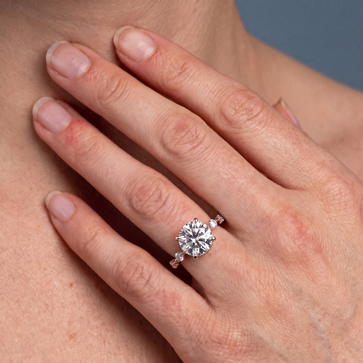 14 KT Rose Gold Round Cut Diamond Solitaire Ring with Floating Diamond Accents - worn close-up