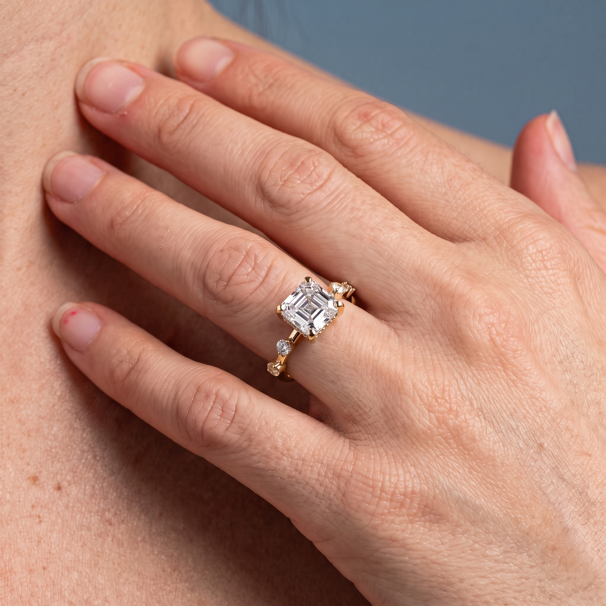 18 KT Yellow Gold Asscher Cut Diamond Solitaire Ring with Floating Diamond Accents - worn close-up