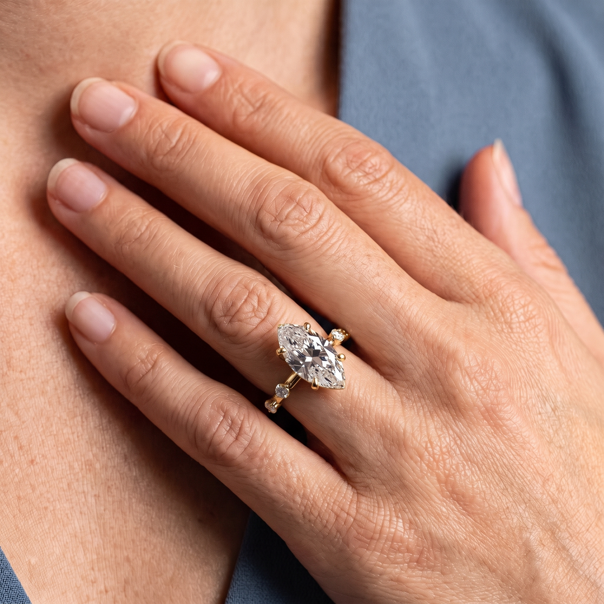 18 KT Yellow Gold Marquise Cut Diamond Solitaire Ring with Floating Diamond Accents - worn close-up
