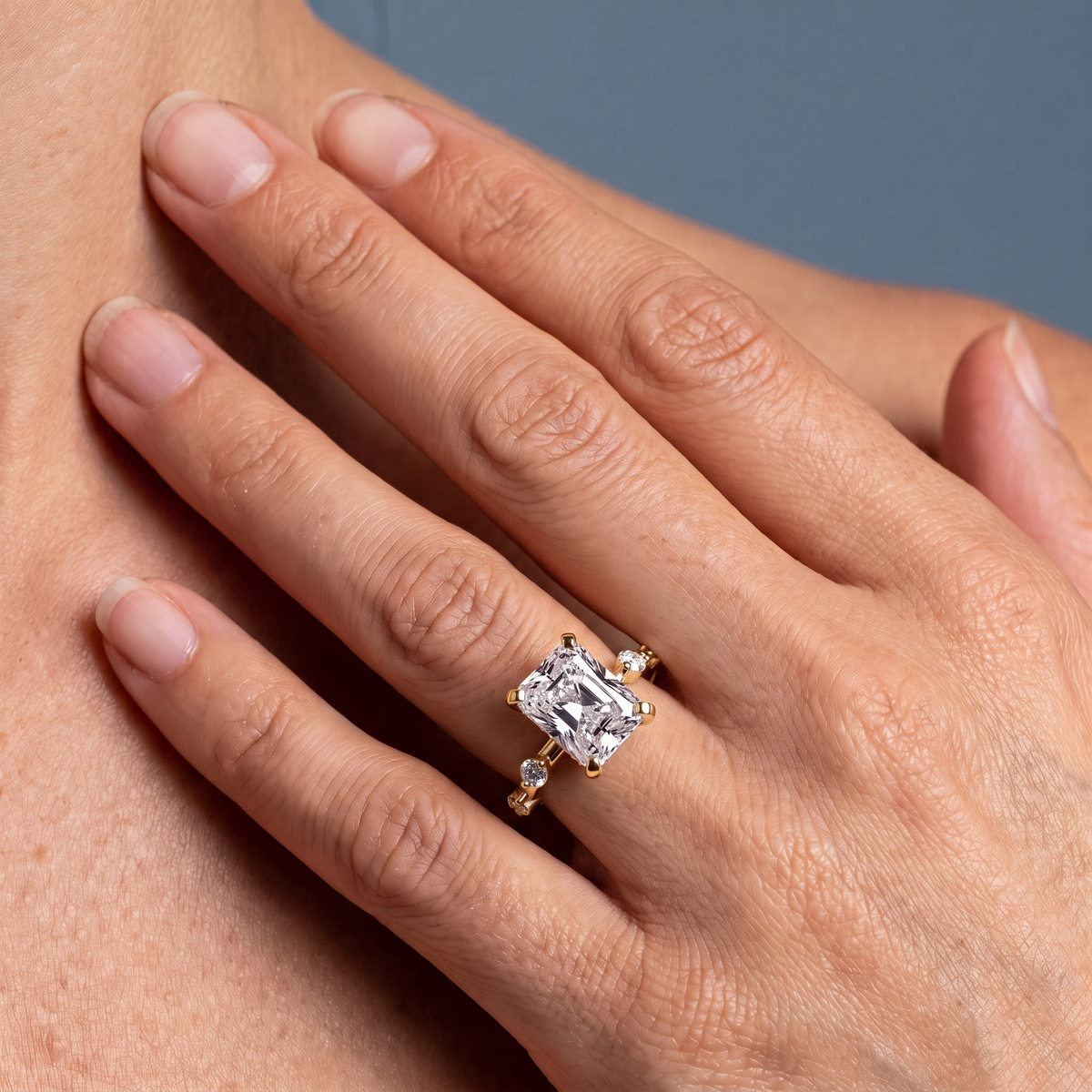 18 KT Yellow Gold Radiant Cut Diamond Solitaire Ring with Floating Diamond Accents - worn close-up