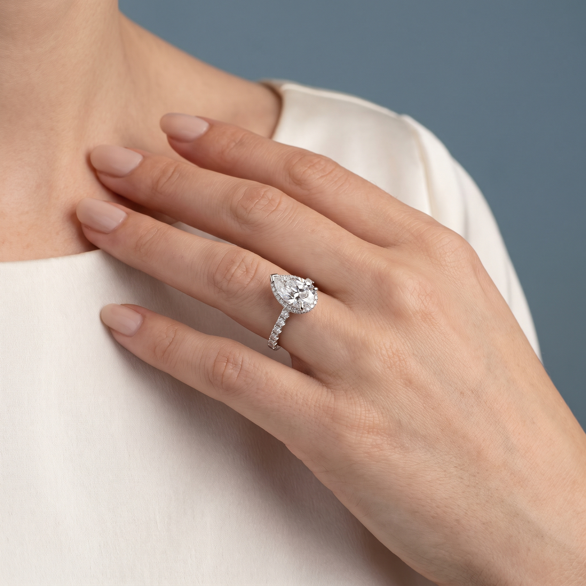 Platinum Pear Cut Diamond Solitaire Ring with Hidden Halo and French Pave Band - worn close-up