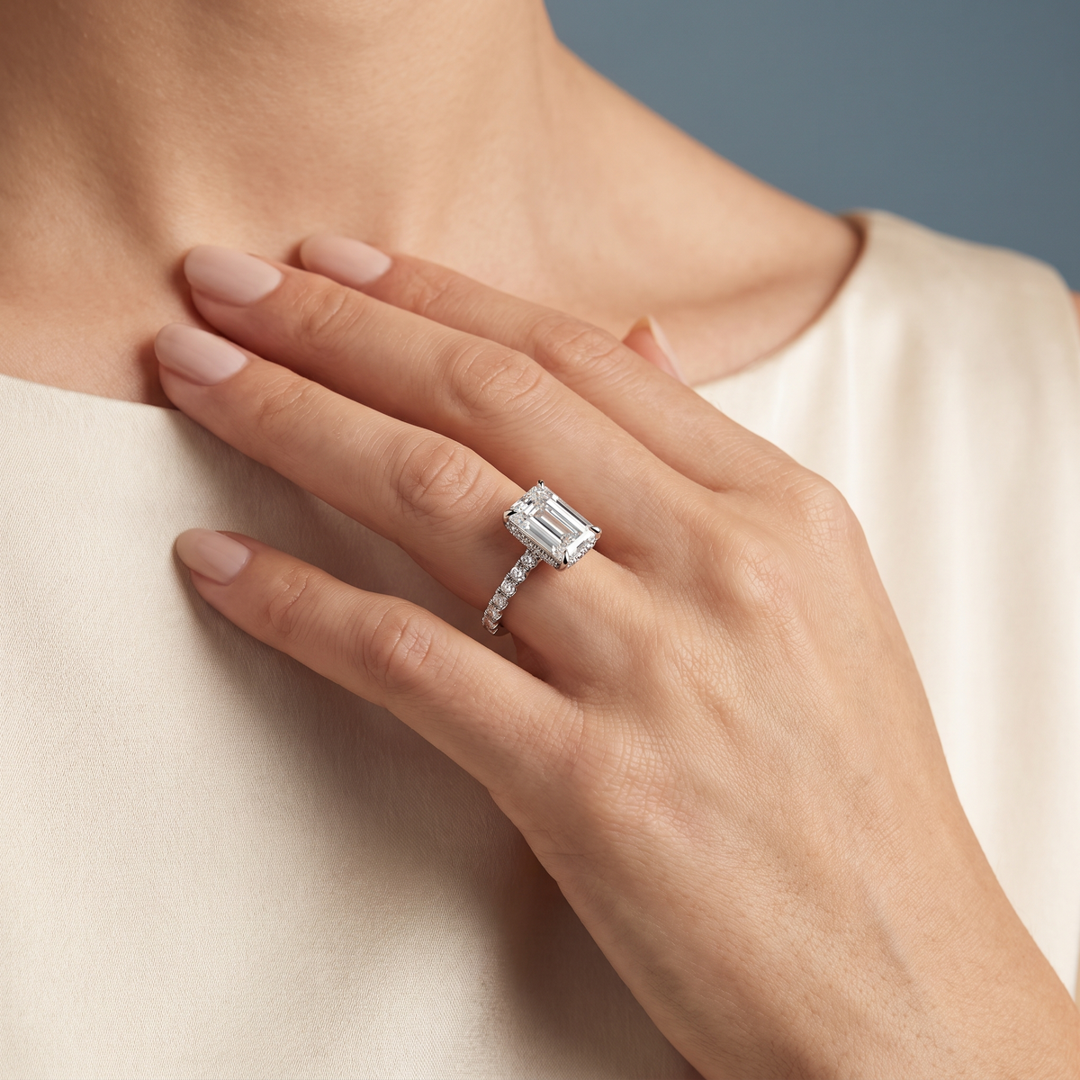 18 KT White Gold Emerald Cut Diamond Solitaire Ring with Hidden Halo and French Pave Band - worn close-up