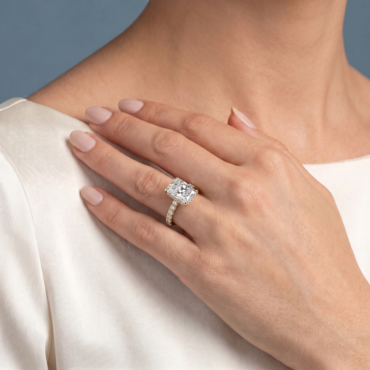 18 KT Yellow Gold Radiant Cut Diamond Solitaire Ring with Hidden Halo and French Pave Band - worn close-up