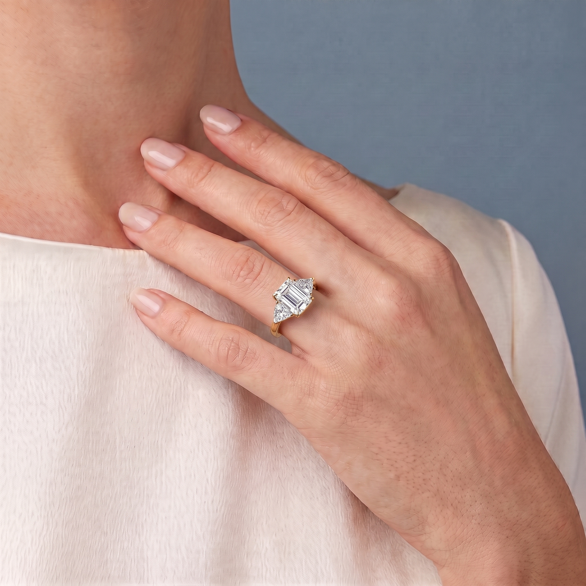 18 KT Yellow Gold Emerald Cut Diamond Three Stone Ring with Trillion Accents - worn close-up